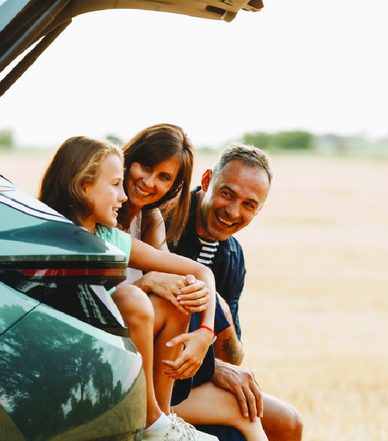 A family beside their car in a field