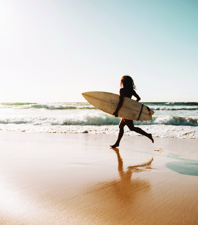A surfer walking along the beach
