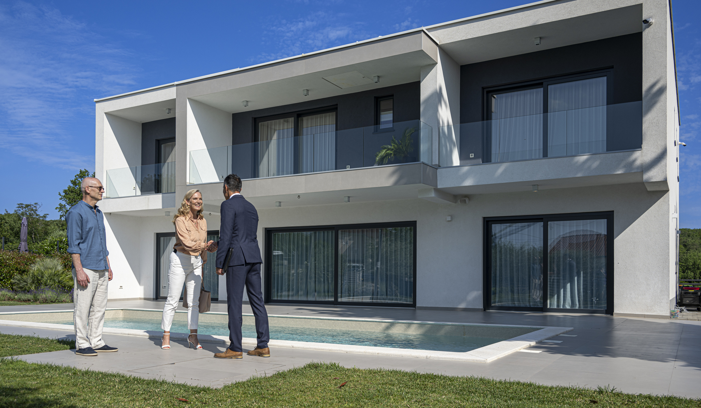 A couple inspecting a modern two-storey home with an agent