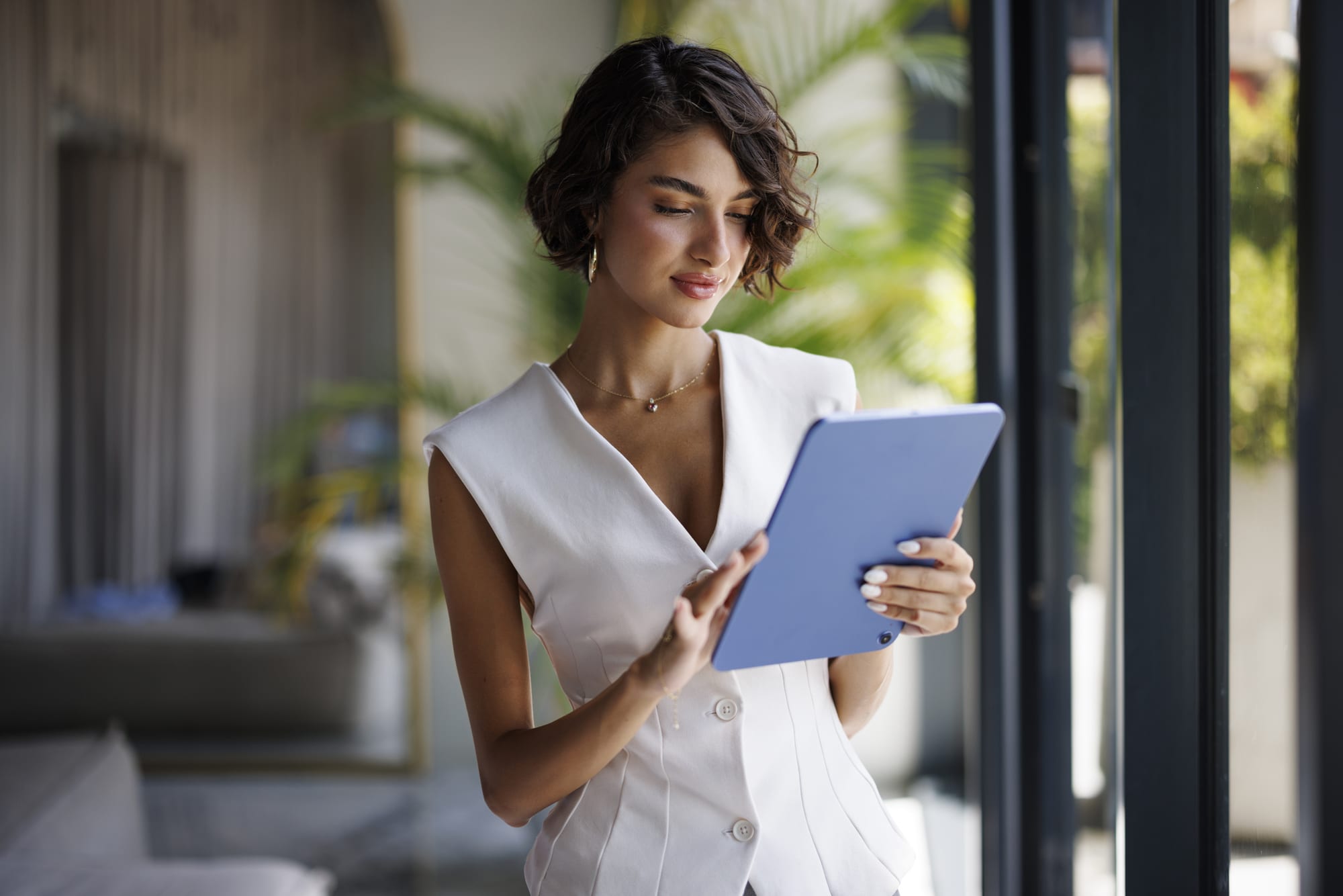 A woman reading on a tablet beside a window